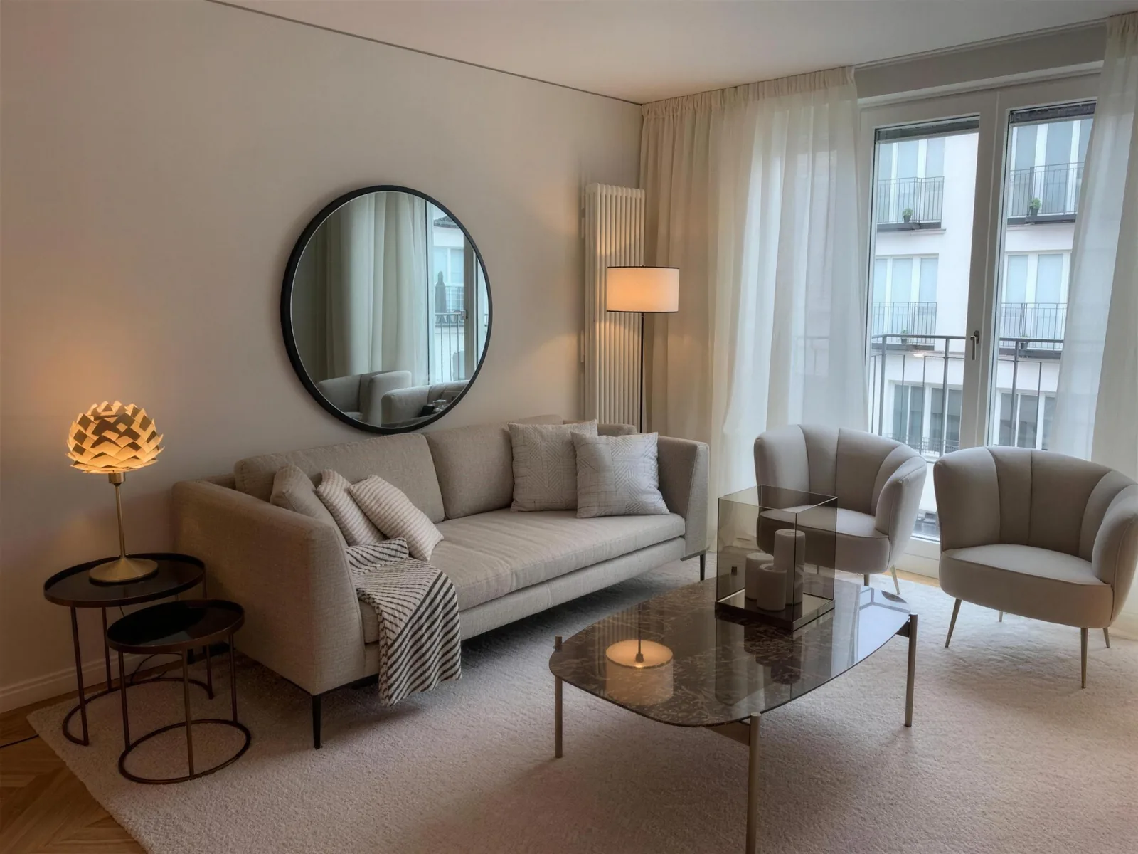 Wohnzimmer in Beige: Sofa, runder Spiegel, Marmor-Couchtisch und Sessel am Fenster