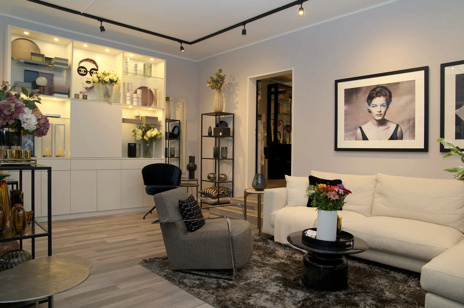 Der STEWARTS-Showroom: helles Sofa, Sessel, Regale mit Accessoires und Schwarz-Weiß-Fotografien an der Wand