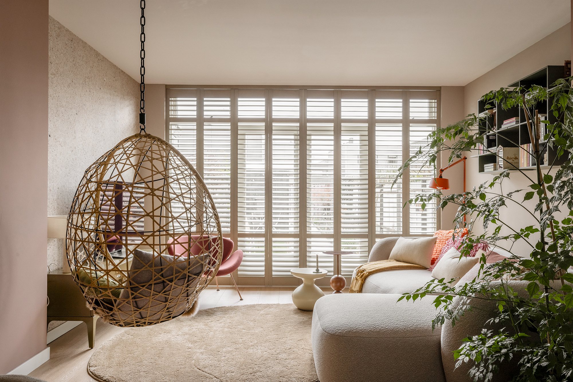 Wohnzimmer mit weißen Shutters vor einer Gartentür, Lamellen leicht geöffnet